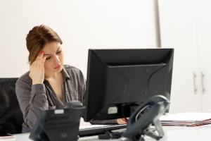 "Mulher de negócios olhando com preocupação para a tela do computador em sua mesa de trabalho, representando estresse ou dificuldade no trabalho."